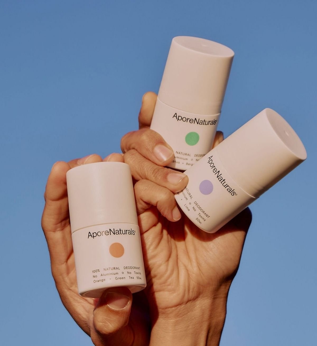 AporeNaturals natural deodorant sticks held up against a blue sky