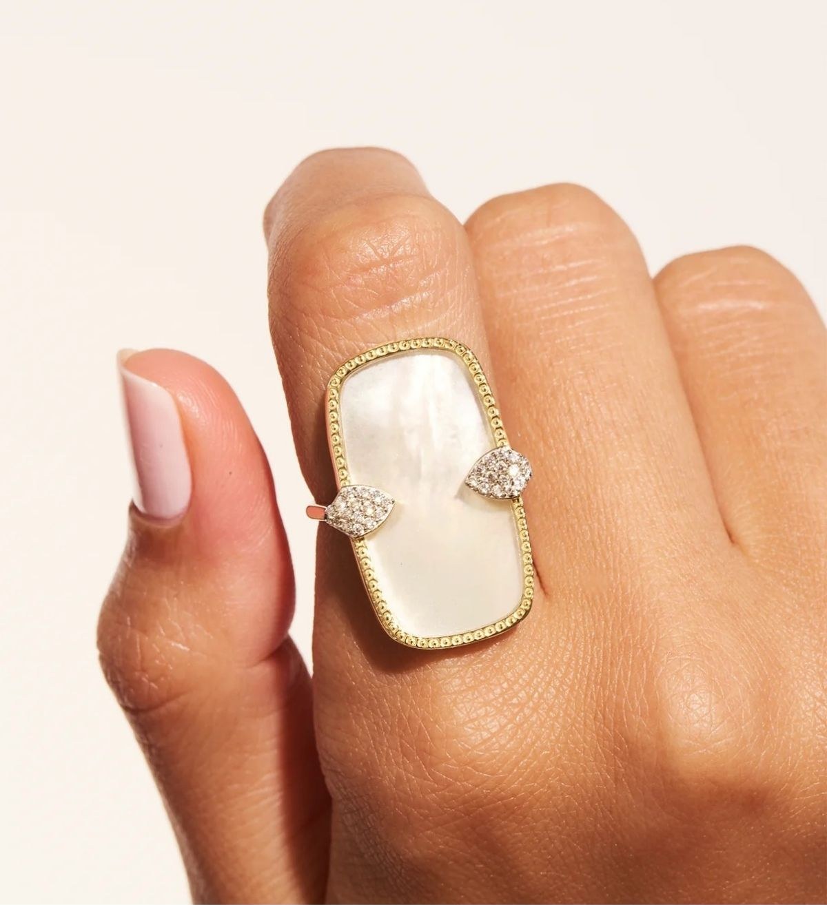 A mother-of-pearl and diamond ring on a hand