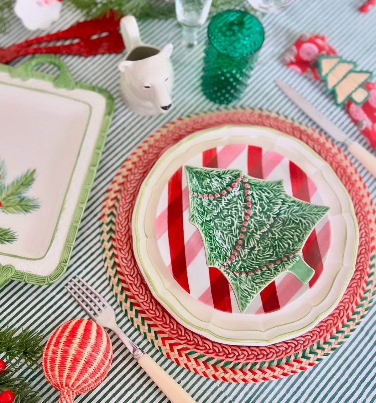A festive table set with a Christmas tree ceramic plate on a red and green striped cloth