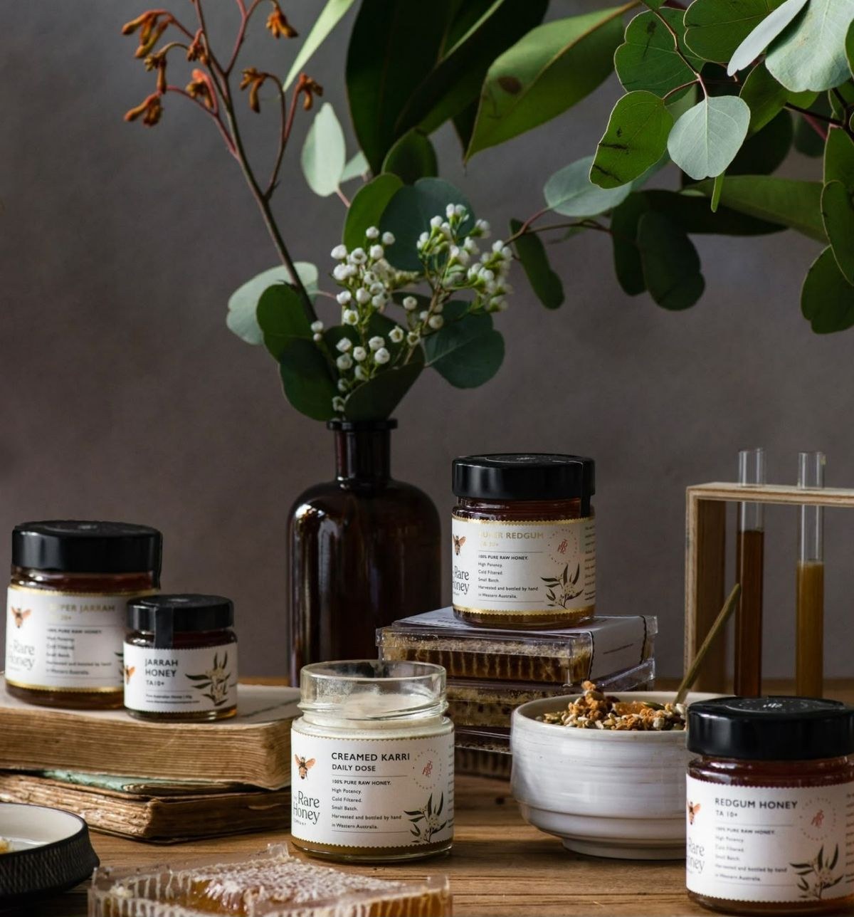 Jars of raw Australian honey on a wooden table with eucalyptus leaves