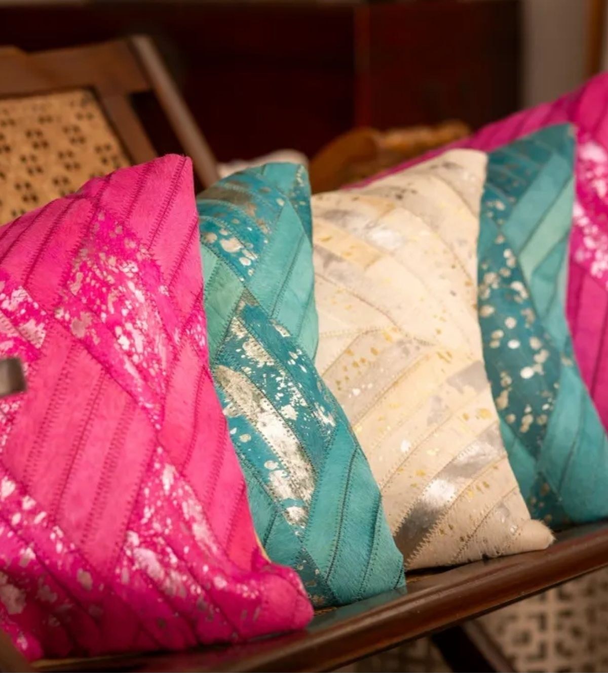 A row of pink, teal and cream patchwork cushions with metallic foil detailing